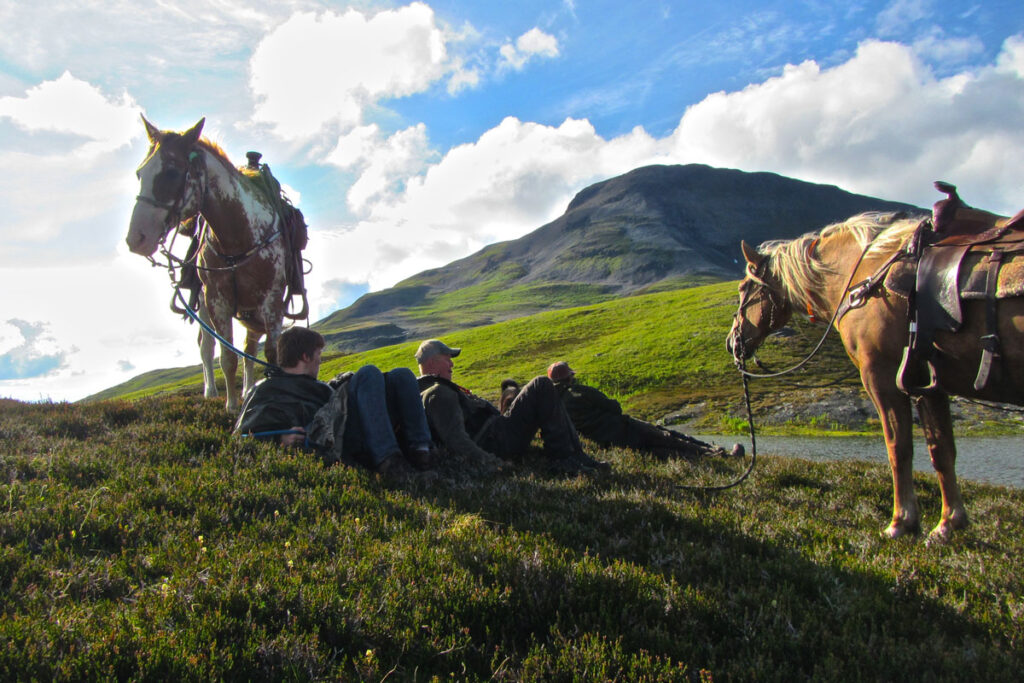 Horses on top of a mountain and riders relaxing